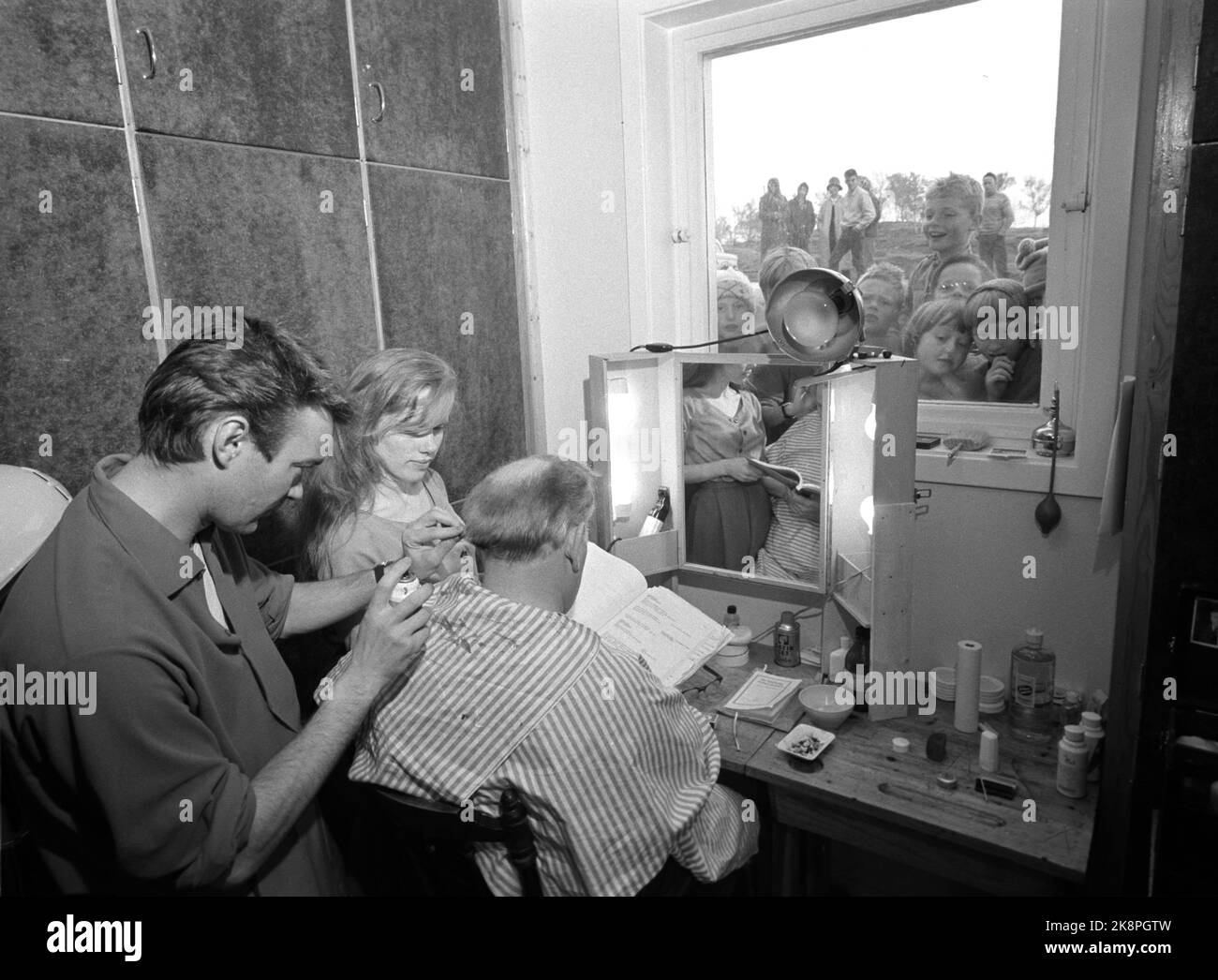 Kjerringøy 19620623. Aufnahme des Films`s Hamsuns 'Pan' auf Kjerringøy. Hier sehen wir Bengt Ottekil, der für die Masken verantwortlich ist, während Liv Ullmann und Glaes Gill, Mack des Films, seine Rollen wiederholen. Neugierige Kinder schauen ins Fenster. Foto: Sverre A. Børretzen Current / NTB Stockfoto